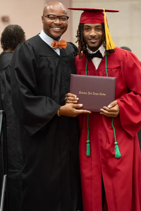 Two African American men pose for a photo after graduation.