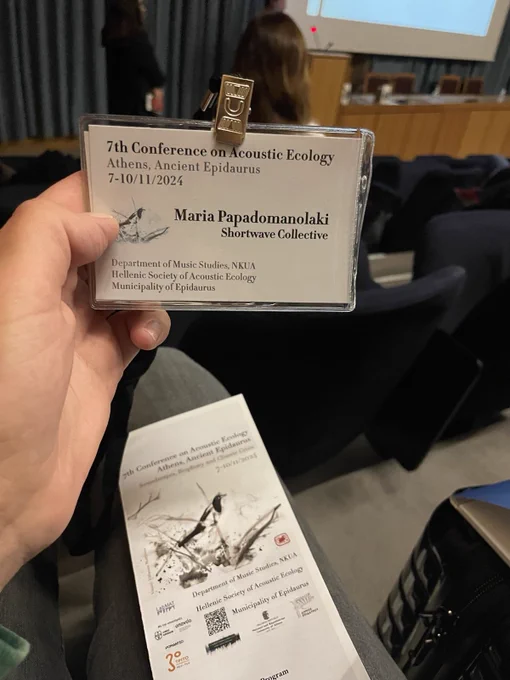 A hand holds a lanyard from a conference that says 'Shortwave Collective'