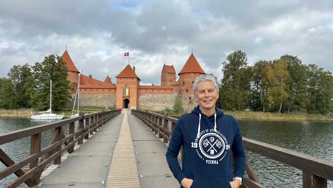 Ein Mann steht auf einer Brücke mit einem Schloss im Hintergrund.