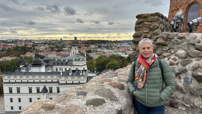 eine Frau, die auf einer Steinmauer steht, mit einer Stadt im Hintergrund