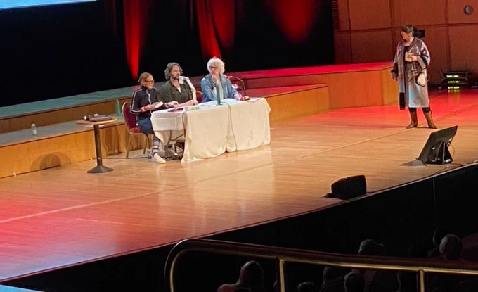 Panel answering questions on stage in large auditorium.