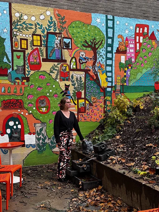 owner of Catzen Coffee, standing on the patio near a mural
