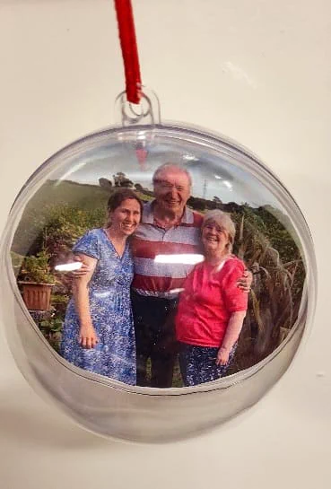 Clear bauble with a photo inside of a man with his arms around two women smiling at the camera.