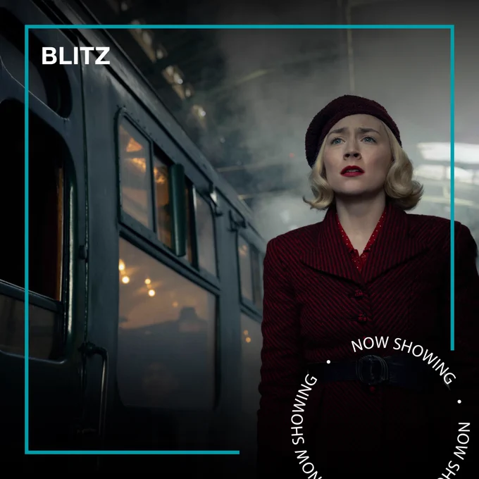 A blonde woman in 1940s clothing stands next to a steam train in a station. Text - Blitz, now showing.
