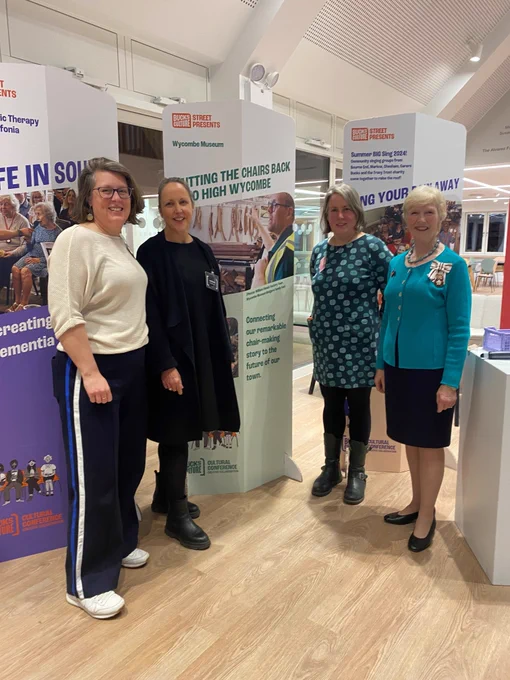 Four women standing in front of a poster.