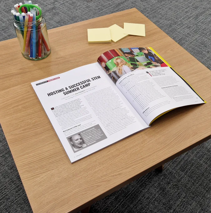 Photo of Hello World, issue 25 open on Alan O'Donohoe's article ' Hosting a successful STEM summer camp' on a coffee table. 
