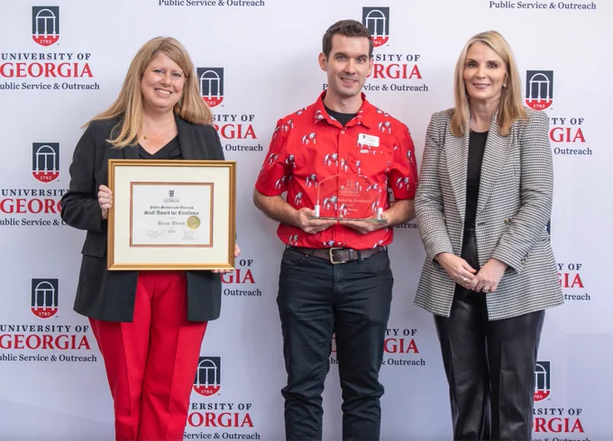 Brian Wrenn of the UGA Center for Continuing Education & Hotel displays his PSO Award of Excellence with Jennifer Frum, vice president of Public Service and Outreach, and Stacy Jones, director of the Georgia Center.