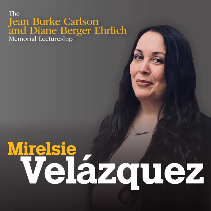 A headshot photo of Mirelsie Velázquez, smiling, wearing a dark blazer and beige top, against a gray background. Text on the photo in the upper left reads: The Jean Burke Carlson and Diane Berger Ehrlich Memorial Lectureship. Toward the bottom of the photo texts reads: Mirelsie Velázquez.