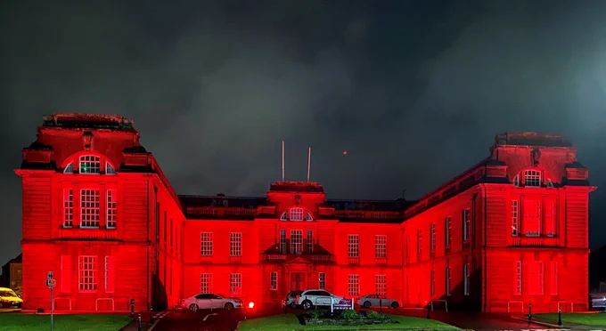 An image of Dumfries and Galloway Council headquarters lit up in red lights