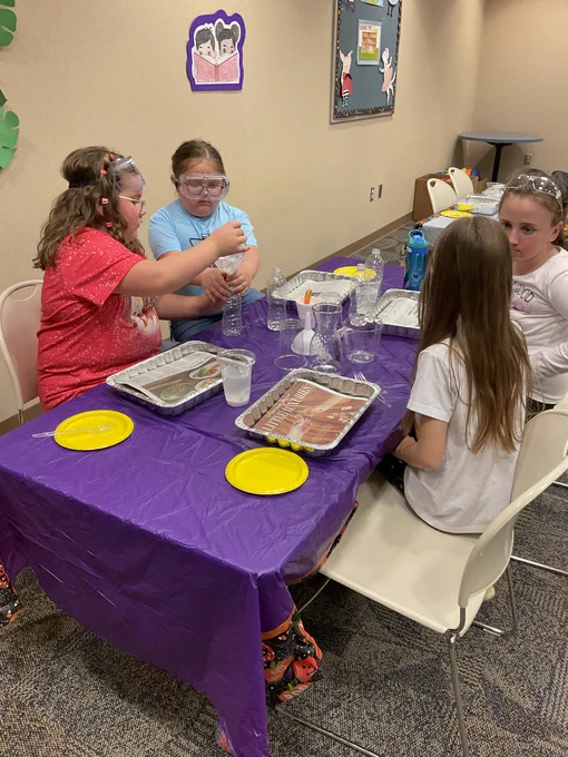 A table of kids helping each other measure ingredients