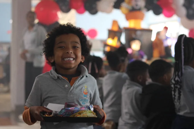 Student smiles while carrying lunch tray. 