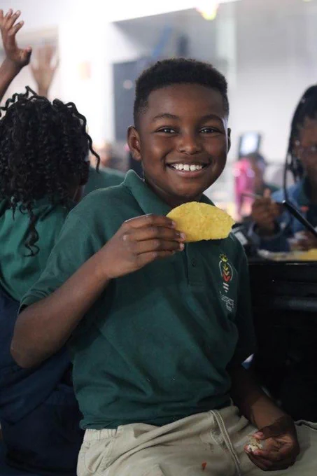 Student smiles while holding a taco that's apart of lunch. 
