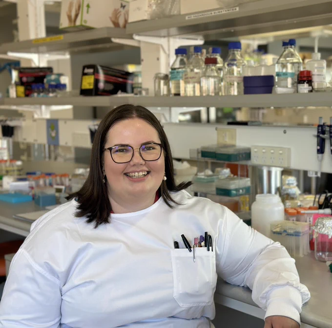 Dr Ella Smalley in a lab, smiling. 