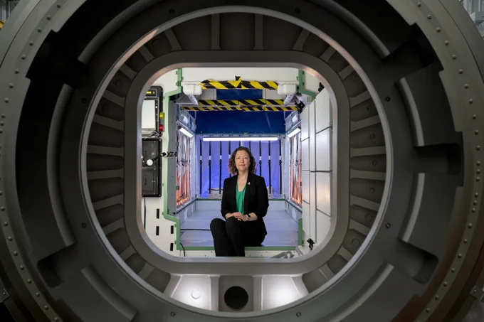 Stephanie Dudley, Gateway's mission integration and utilization manager, sits inside a high-fidelity mockup of HALO (Habitation and Logistics Outpost) at NASA’s Johnson Space Center. She is framed by a docking port, with interior components visible behind her. The mockup’s design showcases the functional environment Artemis astronauts will live and work in while in lunar orbit. Photo credit: NASA/Josh Valcarcel 