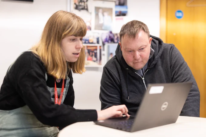 Woman showing something to a man on a laptop screen