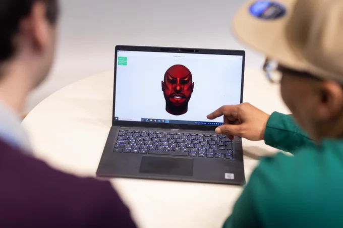 Computerised avatar of an angry man's face on a laptop, someone is pointing at the keyboard