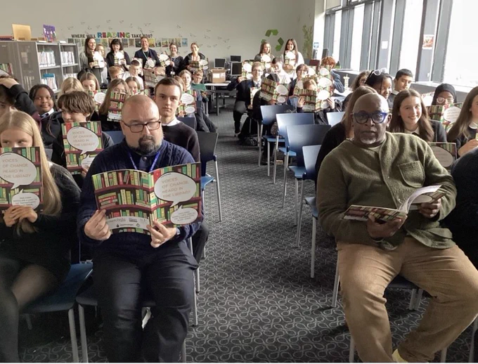 Pupils and staff reading their copies of Voices of Change, Heard in the Library