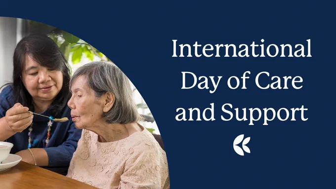 Dark blue background with a middle aged Asian woman feeding an elderly woman. Text: International Day of Care and Support. 