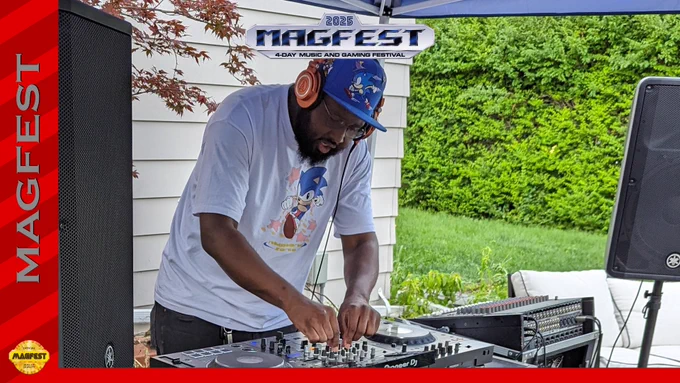 Kuma the Kami stands at his mixer in a Sonic hat and Sonic t-shirt, spinning jams.