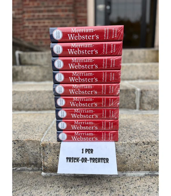 A stack of dictionaries with a sign that says "1 per trick-or-treater"