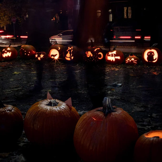 A row of jack o'lanterns in a row at a park.