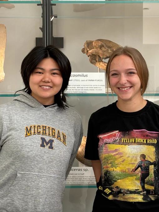 Two people smiling in front of a display case.