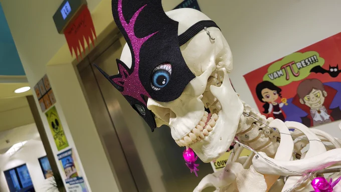 Photo of Moore library skeleton, adorned with a scary mask, bloodshot eyes and glowing spiders