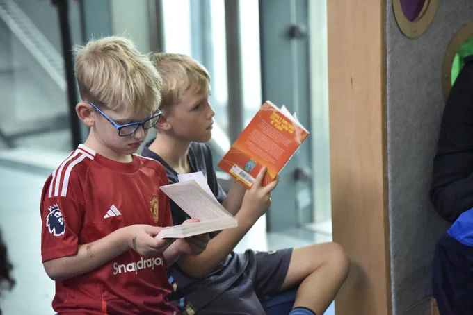 Two young boys reading from books.