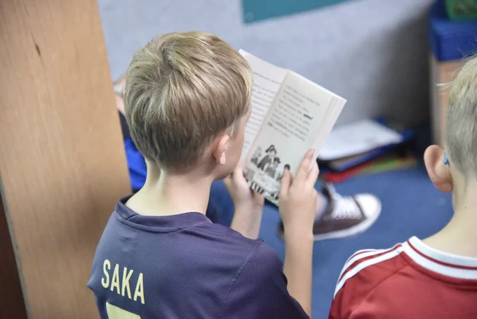 A young boy reading from an open book.