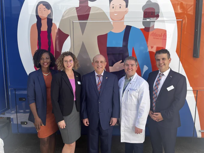 Dr. Licht and four members of the center's leadership pose for a photo in front of the bus.