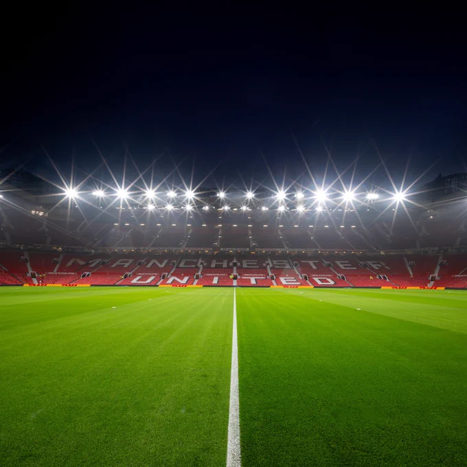 A wide shot of Old Trafford under the lights