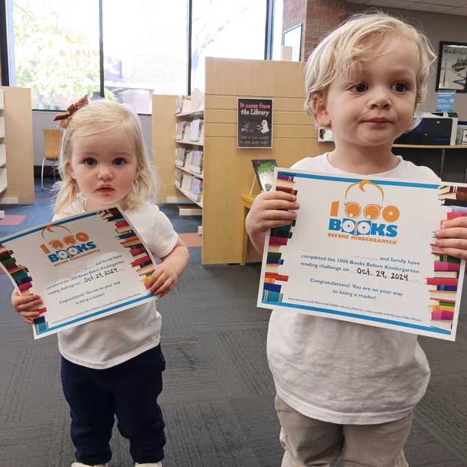 two children holding up their 1000 books before kindergarten finishing certificates.