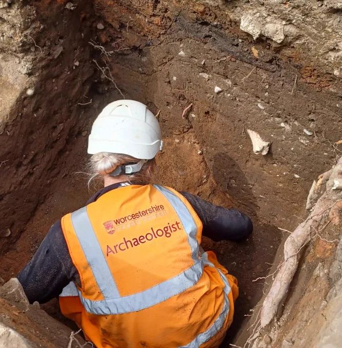 Archaeologist digging within a test pit.