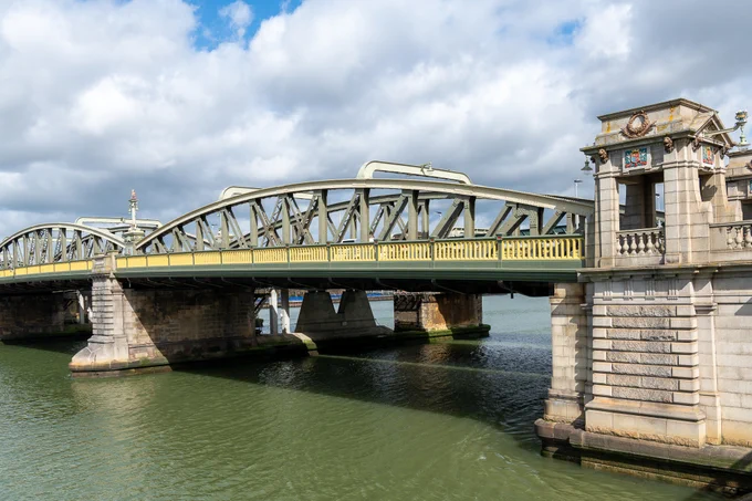 A photograph of Rochester Bridge. The Old Bridge is a bowstring-shaped truss bridge, with two spans visible in this picture.