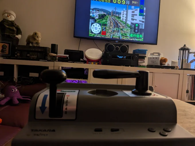 A sega Saturn Densha Da Go controller in the foreground, and Densa Da Go! EX on a TV in the background 