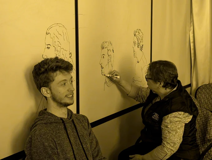 Picture of an attendee getting his portrait drawn. The lighting from the sodium lamp makes the scene colorless. 