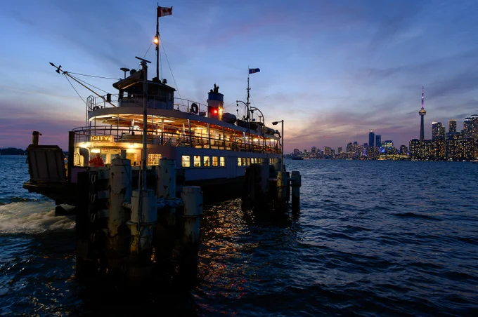 ferry about to dock, with sunset and skyline behind
