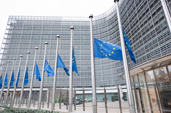 A series of 11 European flags at half mast in front of the facade of the Berlaymont building in Brussels.