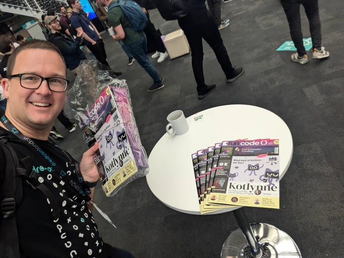 A few copies of the fun code() magazine lying on a table at Droidcon London. 
Marc Reichelt can be seen next to the table, holding more magazines and smiling.