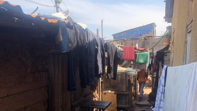 A corridor in Kisenyi informal settlement in Kampala, with a semi-permanent hostel and a permanent structure.