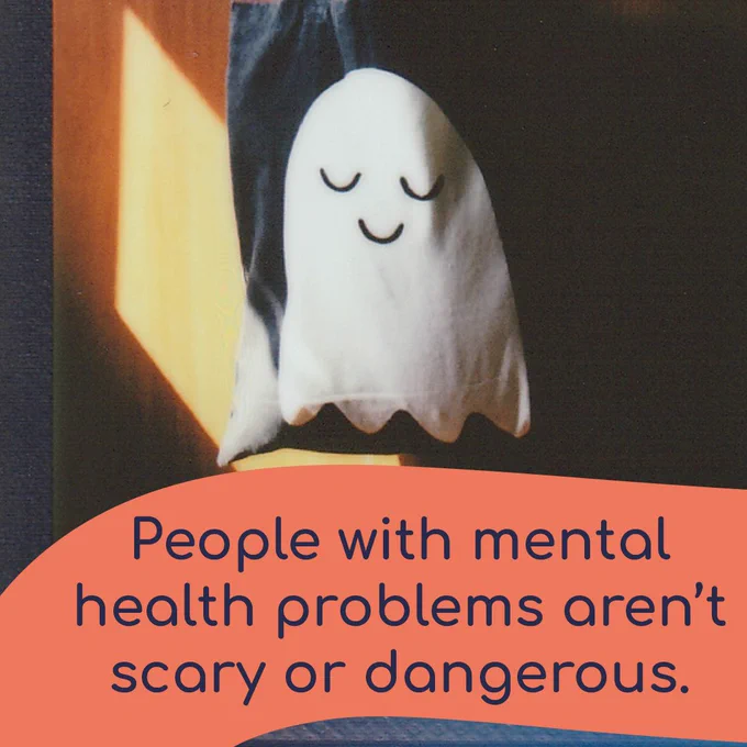 People with mental health problems aren’t scary or dangerous. The background is a photo of a canvas bag with a smiling ghost on it.  
