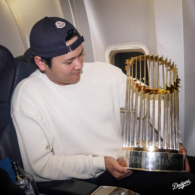 Shohei Ohtani looks at the World Series trophy on the plane.