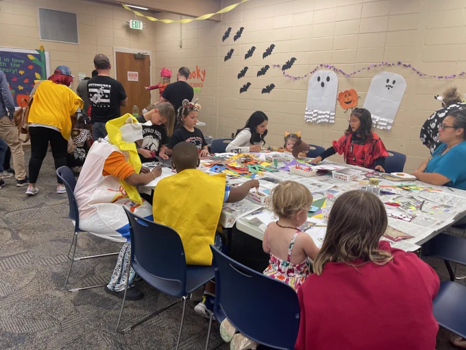 Adults and kids in costumes making crafts around a table