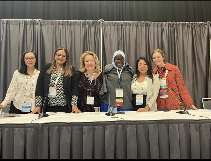 Session speakers at the Evaluation 2024 Conference, standing behind a desk and smiling