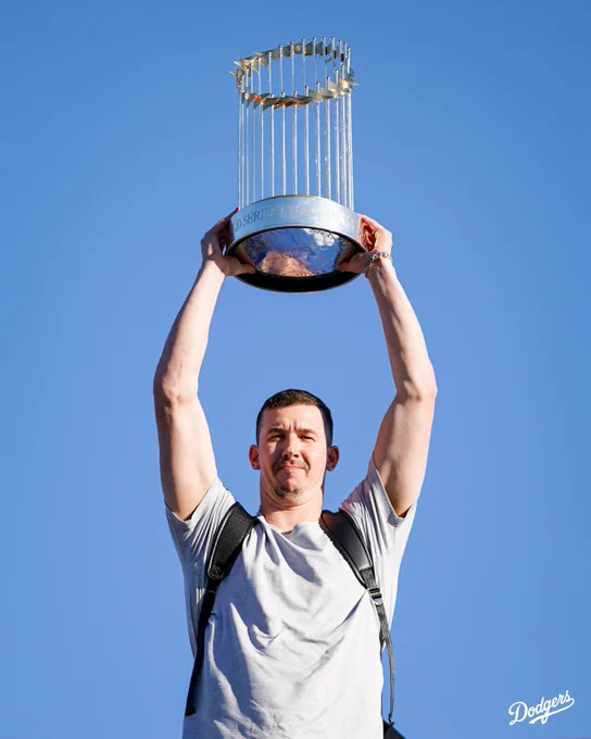 Walker Buehler arrives in Los Angeles and holds up the World Series trophy.