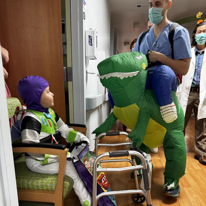 Little boy dressed as buzz lightyear getting treats in hospital hallway