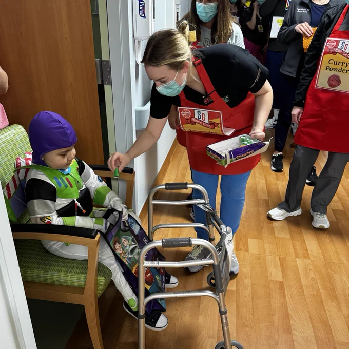 Little boy dressed as buzz lightyear getting treats in hospital hallway