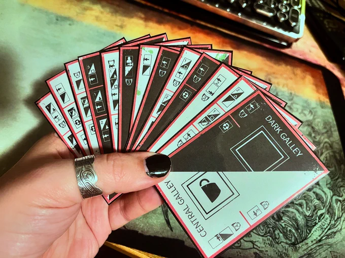 Photo of my hand holding 13 sleeved cards describing ship modules, each with a light and dark side, and action icons on the side directed you what to do. 