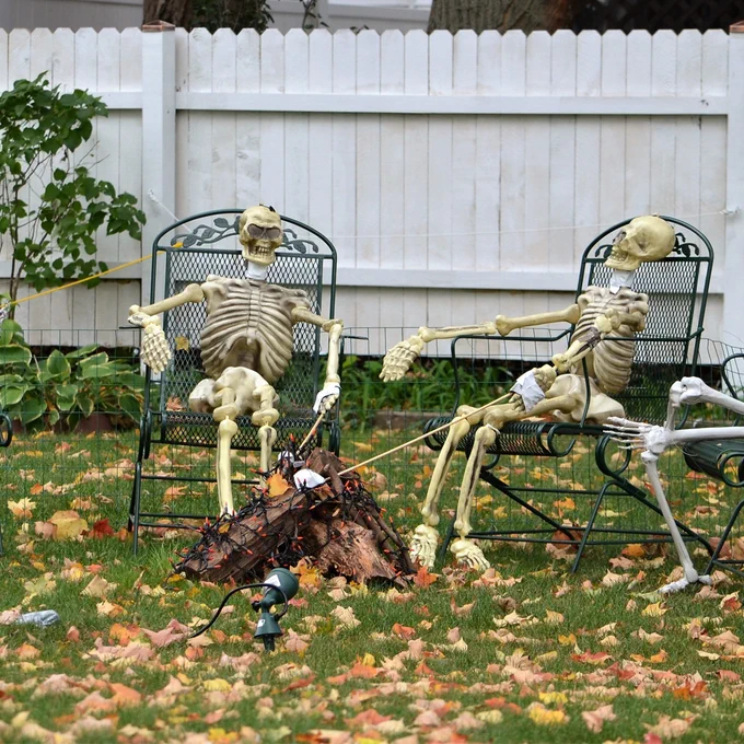 Two skeletons relax in outdoor chairs among the fallen leaves