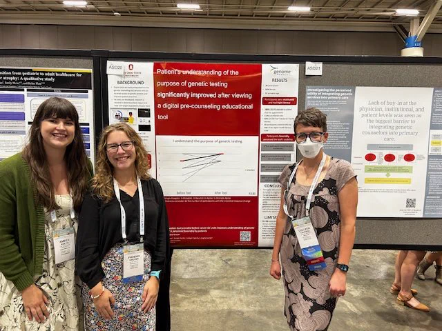 Amber and Phoenix stand on the left of Phoenix’s research poster and Colleen stands on the right. They are all looking at the camera and smiling
